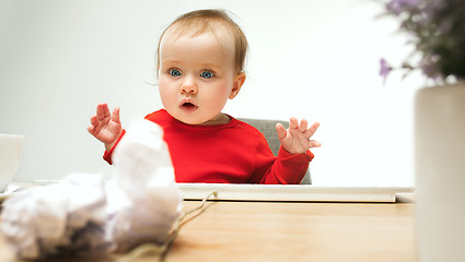 Image showing Happy child baby girl toddler sitting with keyboard of computer isolated on a white background