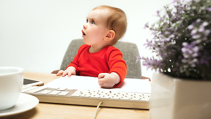 Image showing Happy child baby girl toddler sitting with keyboard of computer isolated on a white background