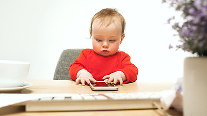 Image showing Happy child baby girl toddler sitting with keyboard of computer isolated on a white background