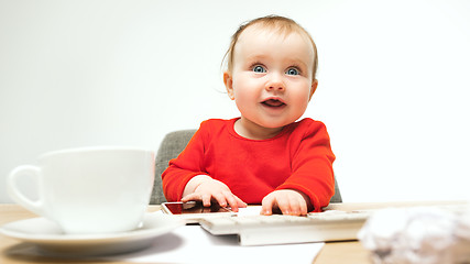 Image showing Happy child baby girl toddler sitting with keyboard of computer isolated on a white background