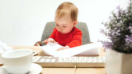 Image showing Happy child baby girl toddler sitting with keyboard of computer isolated on a white background