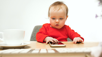 Image showing Happy child baby girl toddler sitting with keyboard of computer isolated on a white background