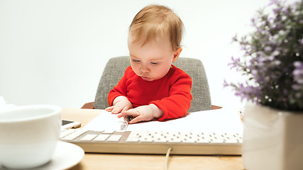 Image showing Happy child baby girl toddler sitting with keyboard of computer isolated on a white background