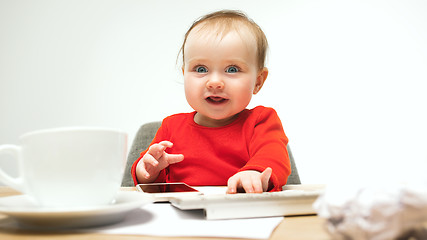 Image showing Happy child baby girl toddler sitting with keyboard of computer isolated on a white background