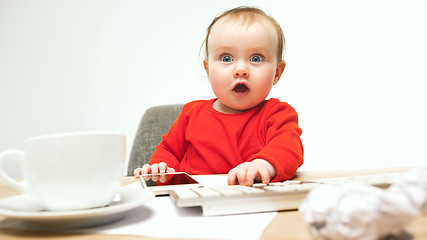 Image showing Happy child baby girl toddler sitting with keyboard of computer isolated on a white background