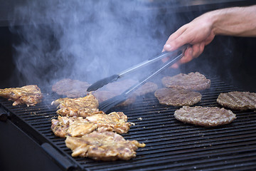 Image showing Chef preparing burgers at the barbecue outdoors