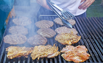 Image showing Chef preparing burgers at the barbecue outdoors