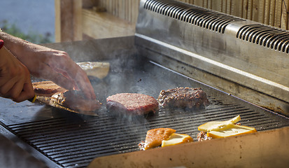 Image showing Chef preparing burgers at the barbecue outdoors