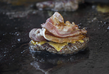 Image showing Preparing burgers with bacon at the barbecue outdoors