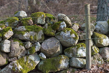 Image showing Barbed wire by an old stone wall