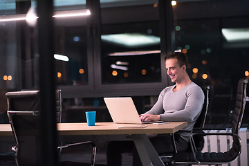 Image showing man working on laptop in dark office