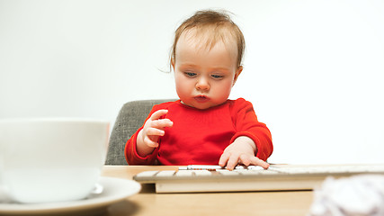 Image showing Happy child baby girl toddler sitting with keyboard of computer isolated on a white background