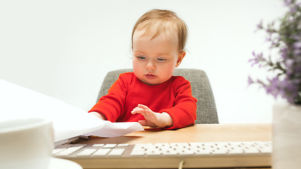 Image showing Happy child baby girl toddler sitting with keyboard of computer isolated on a white background