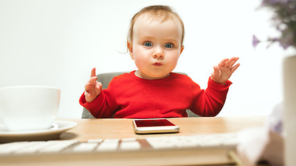 Image showing Happy child baby girl toddler sitting with keyboard of computer isolated on a white background