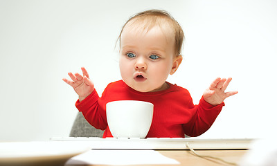 Image showing Happy child baby girl toddler sitting with keyboard of computer isolated on a white background