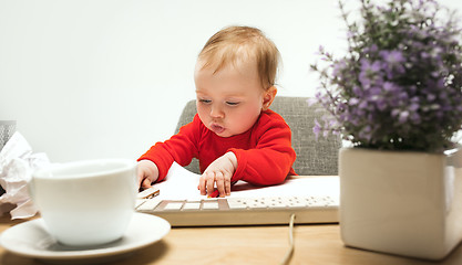 Image showing Happy child baby girl toddler sitting with keyboard of computer isolated on a white background