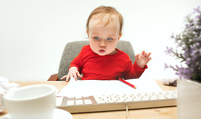 Image showing Happy child baby girl toddler sitting with keyboard of computer isolated on a white background