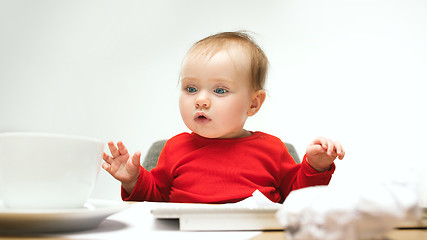 Image showing Happy child baby girl toddler sitting with keyboard of computer isolated on a white background