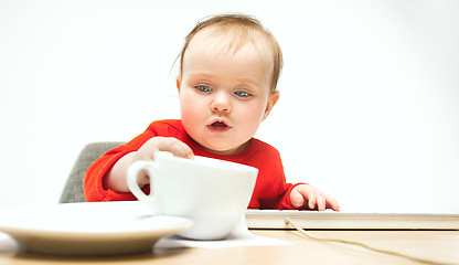 Image showing Happy child baby girl toddler sitting with keyboard of computer isolated on a white background