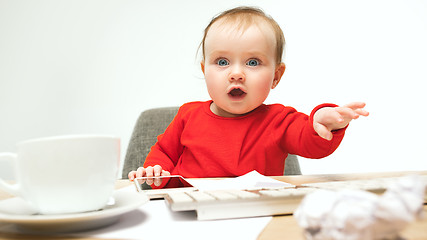 Image showing Happy child baby girl toddler sitting with keyboard of computer isolated on a white background