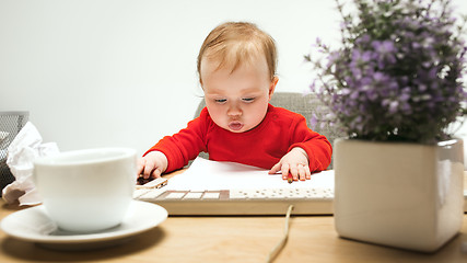 Image showing Happy child baby girl toddler sitting with keyboard of computer isolated on a white background