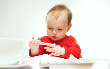 Image showing Happy child baby girl toddler sitting with keyboard of computer isolated on a white background