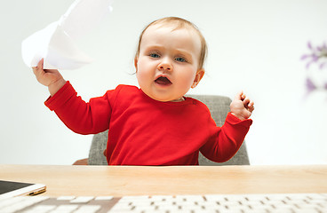 Image showing Happy child baby girl toddler sitting with keyboard of computer isolated on a white background