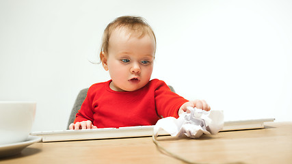 Image showing Happy child baby girl toddler sitting with keyboard of computer isolated on a white background