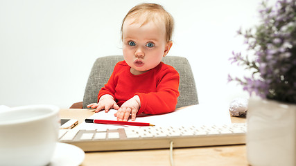 Image showing Happy child baby girl toddler sitting with keyboard of computer isolated on a white background