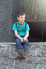 Image showing Boy Sitting on the ground Outdoors