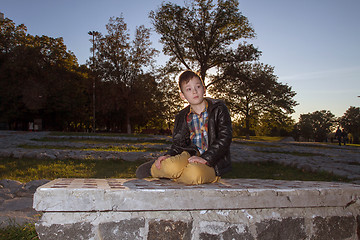 Image showing Boy Sitting on the ground Outdoors