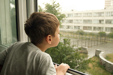 Image showing Boy watching the rain through the window