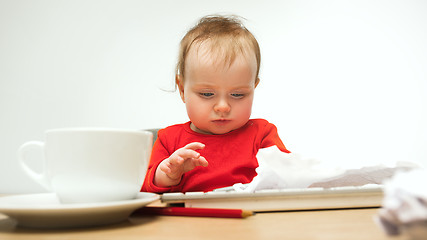 Image showing Happy child baby girl toddler sitting with keyboard of computer isolated on a white background