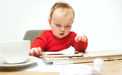 Image showing Happy child baby girl toddler sitting with keyboard of computer isolated on a white background