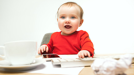 Image showing Happy child baby girl toddler sitting with keyboard of computer isolated on a white background