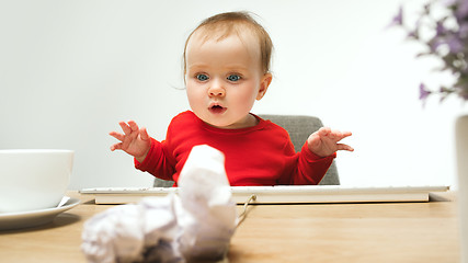 Image showing Happy child baby girl toddler sitting with keyboard of computer isolated on a white background