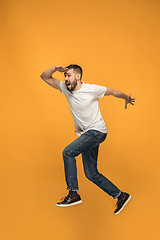 Image showing Freedom in moving. handsome young man jumping against orange background