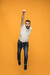 Image showing Freedom in moving. handsome young man jumping against orange background