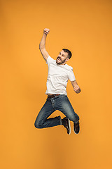 Image showing Freedom in moving. handsome young man jumping against orange background