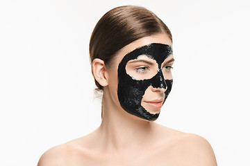 Image showing Young beautiful woman applying a mask for the face of the therapeutic black mud. Spa treatment