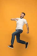 Image showing Freedom in moving. handsome young man jumping against orange background