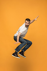 Image showing Freedom in moving. handsome young man jumping against orange background