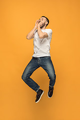 Image showing Freedom in moving. handsome young man jumping against orange background