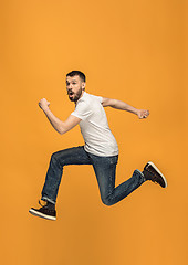 Image showing Freedom in moving. handsome young man jumping against orange background