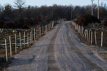 Image showing Gravel road with fence and snow stakes