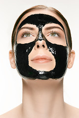 Image showing Young beautiful woman applying a mask for the face of the therapeutic black mud. Spa treatment