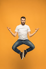 Image showing Freedom in moving. handsome young man jumping against orange background