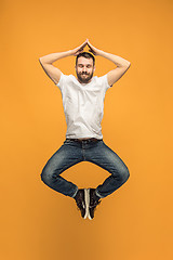 Image showing Freedom in moving. handsome young man jumping against orange background