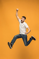 Image showing Freedom in moving. handsome young man jumping against orange background