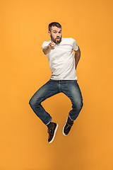 Image showing Freedom in moving. handsome young man jumping against orange background